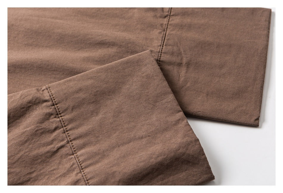 Close-up of brown garment panels with topstitching and a wide folded edge.