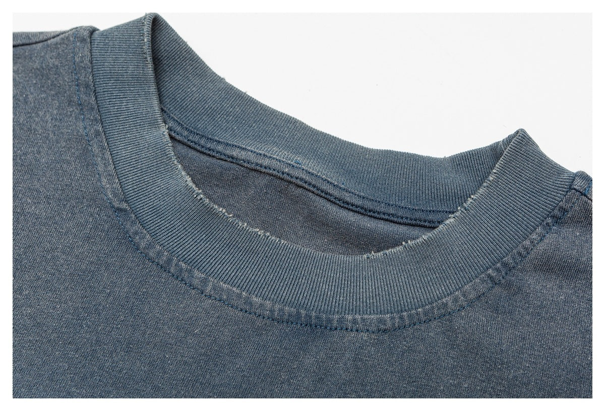 Close-up of a blue-gray shirt's ribbed crew neckline and shoulder seam.