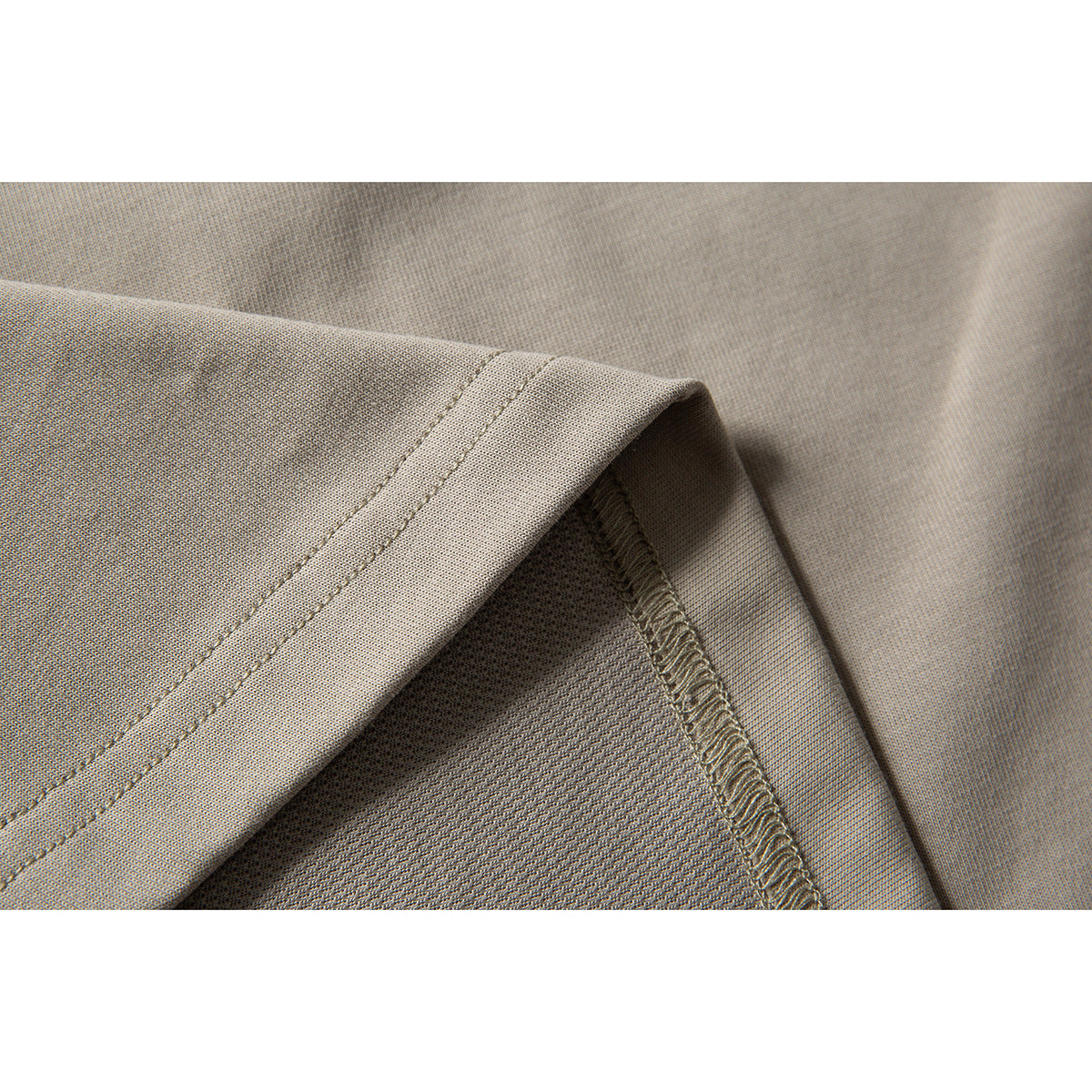 Close-up showing the taupe T-shirt's fabric, folded edge, and interior seam stitching.