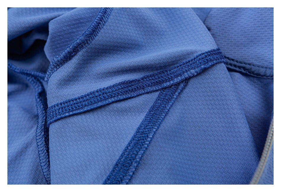 Blue garment close-up showing intersecting stitched seams and a zipper edge.