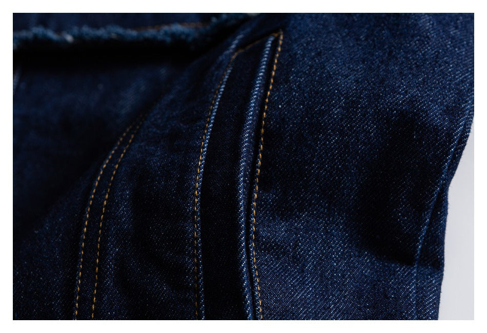 Close-up of dark indigo denim seams with parallel gold stitching.