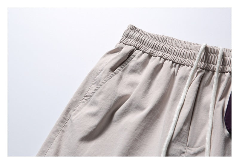 Close-up of the elastic waistband, white drawcords, and angled pocket on light beige shorts.