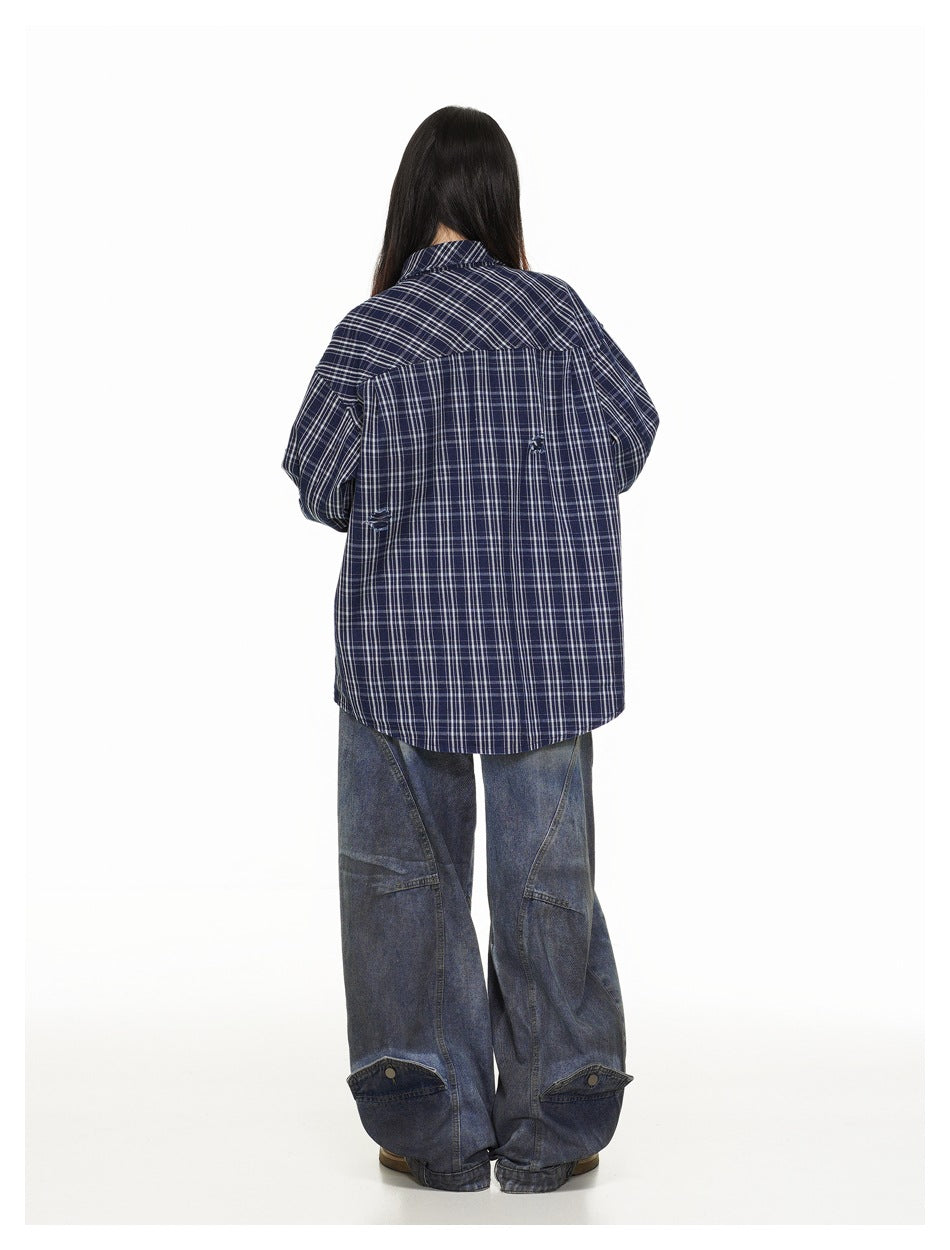 Back view of a model wearing an oversized navy plaid shirt and loose dark jeans.