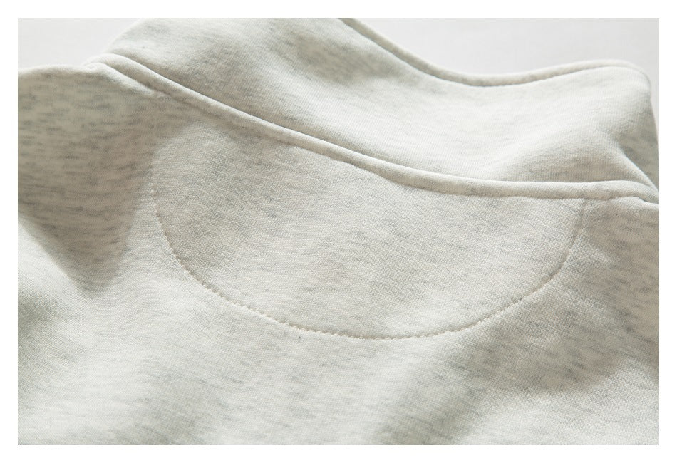 Close-up of a rounded neckline and stitching on a pale gray marled garment.