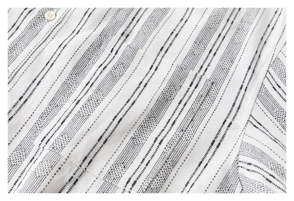 Close-up of a cream shirt's black stripe pattern, chest pocket, and button placket.