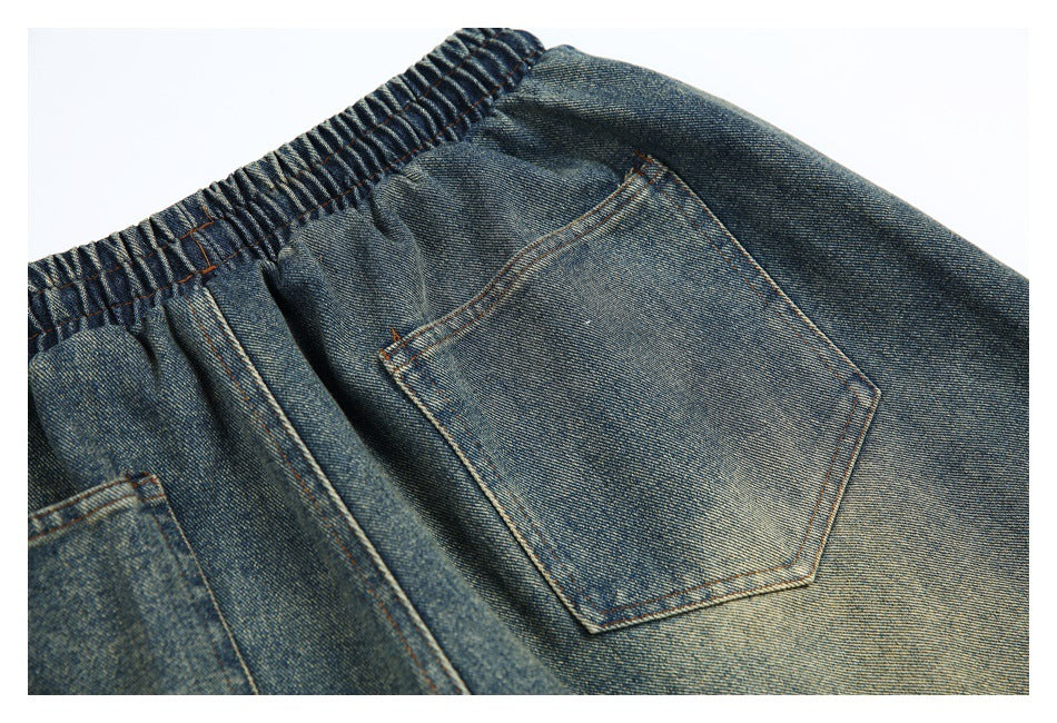 Close-up of a smaller stitched pocket and gathered waistband on faded blue denim shorts.