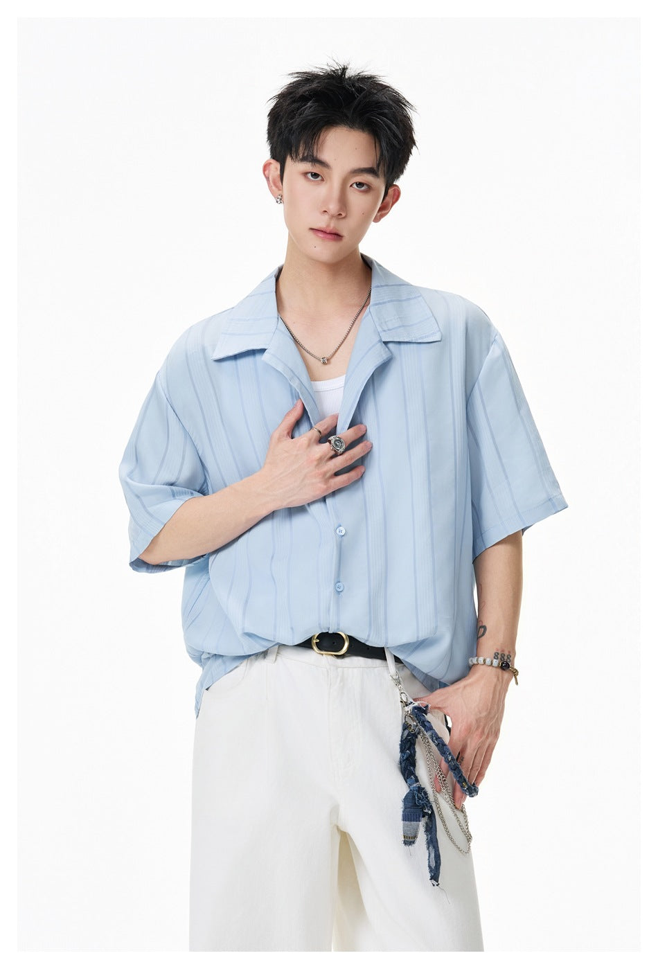 Model wearing a light-blue short-sleeve shirt with vertical stripes and white trousers.