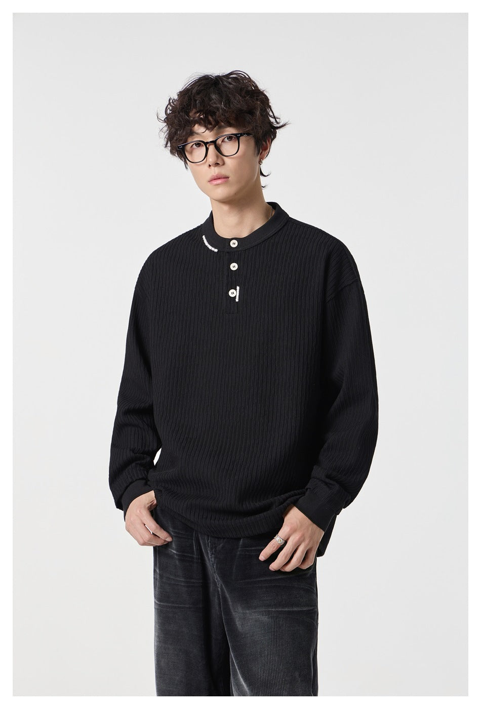 Close view of a model wearing a black ribbed Henley with a short button placket and white accents.