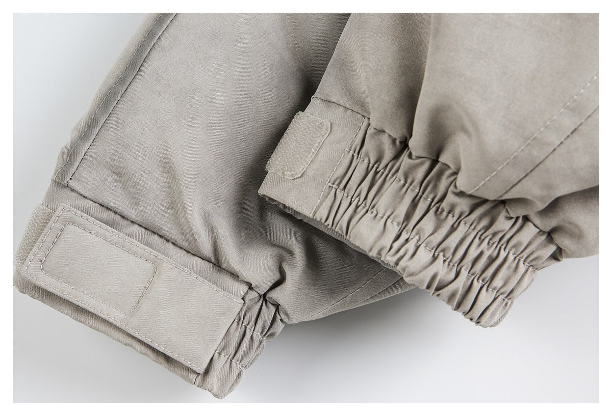 Close-up of a taupe-gray jacket's gathered elastic cuffs and hook-and-loop adjustment tabs.
