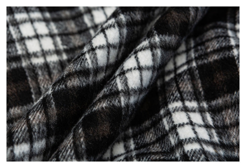 Close-up of folded black, gray, and white plaid fabric showing its fuzzy surface and pattern.