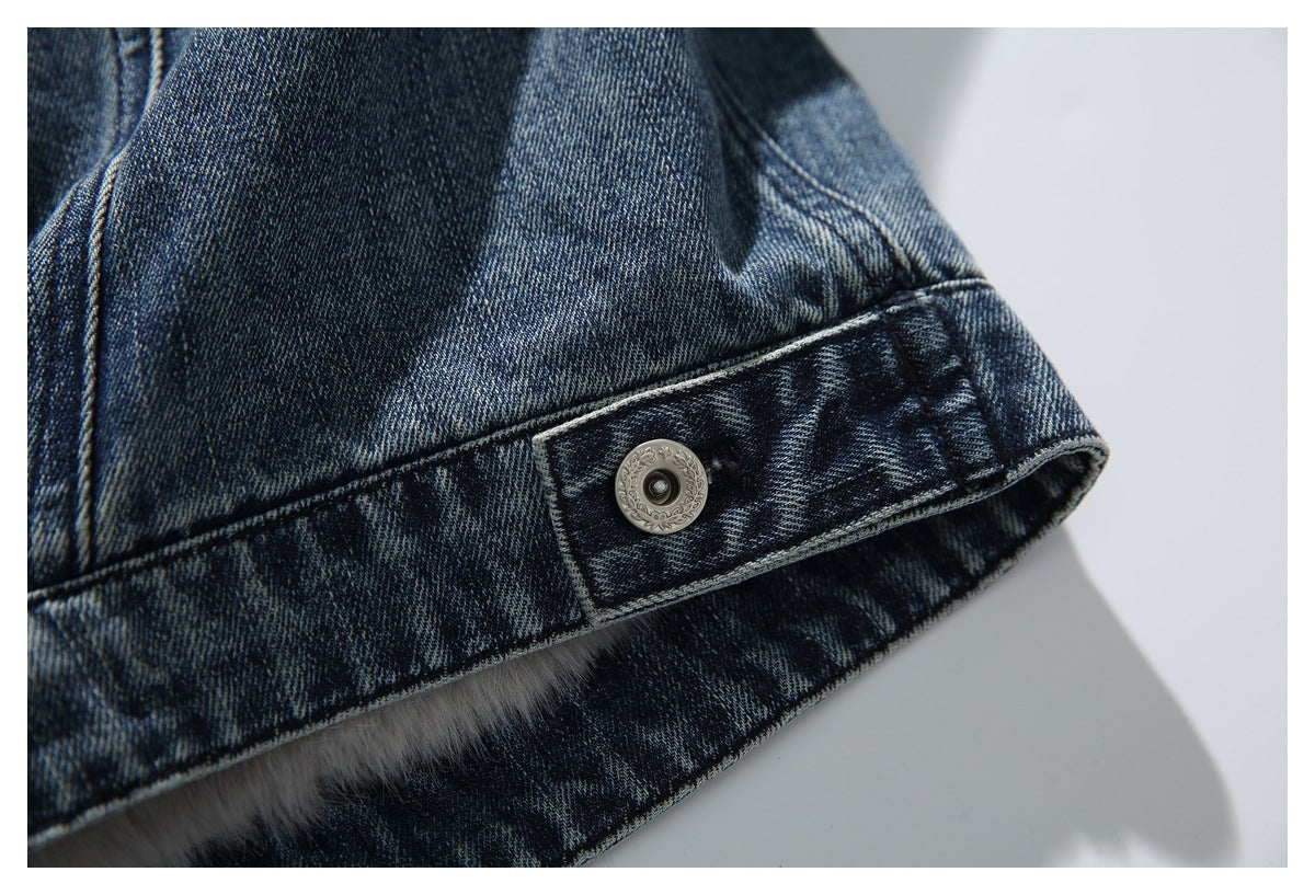 Ornate metal snap on a washed denim jacket hem, with a glimpse of light lining underneath.