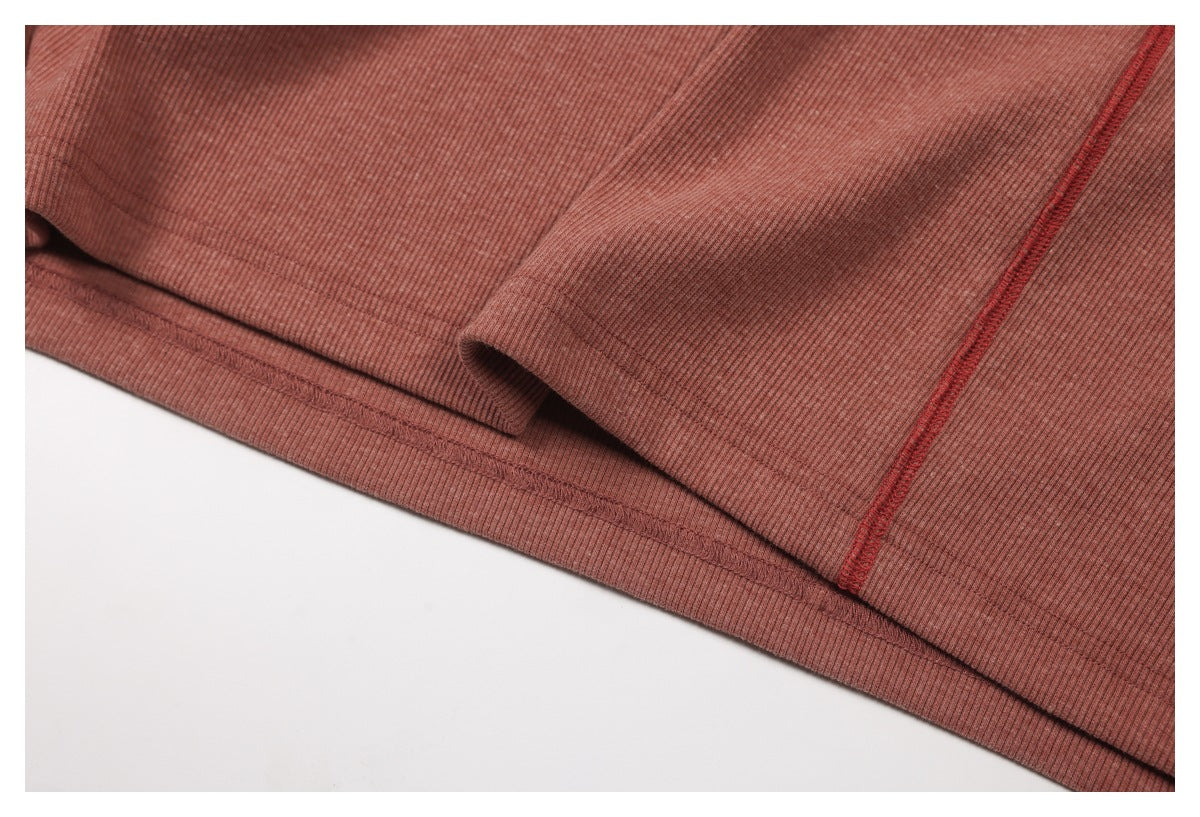 Close-up of the dusty rose ribbed top's folded hem and contrasting red seam stitching.