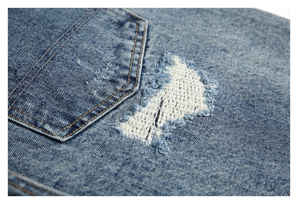 Close-up of a white repaired distressed patch beside a back pocket on blue denim.