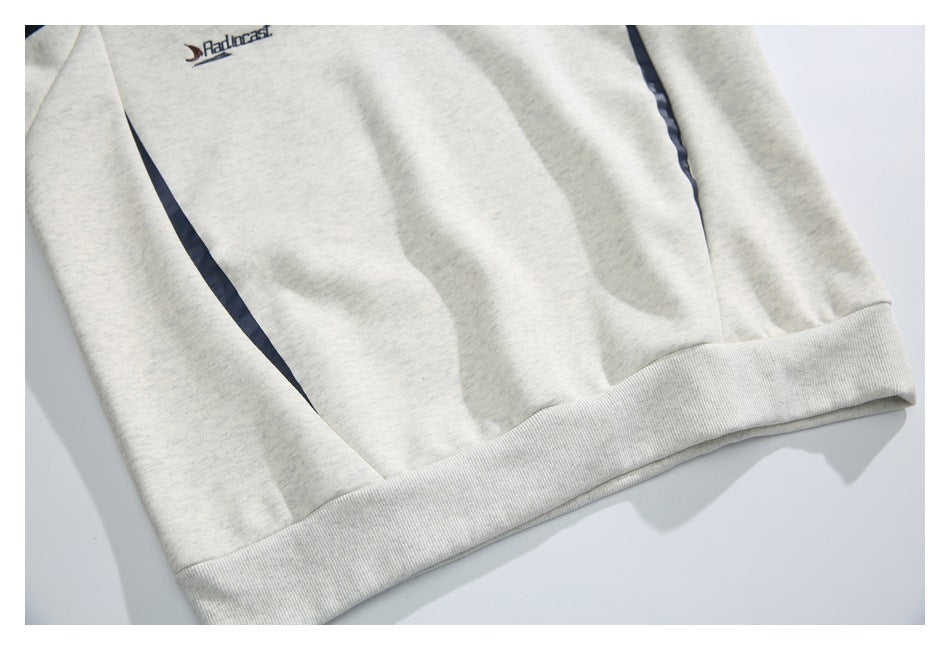 Close-up of a light gray heather sweatshirt hem with a navy accent stripe and small embroidered chest logo.