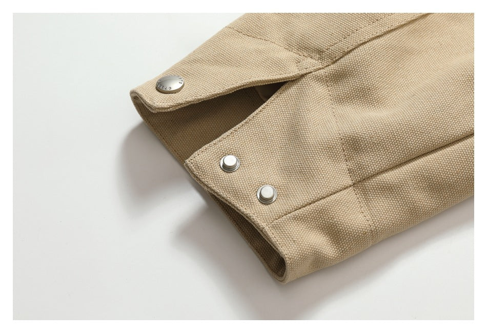 Close-up of a beige garment cuff with three silver snap fasteners.