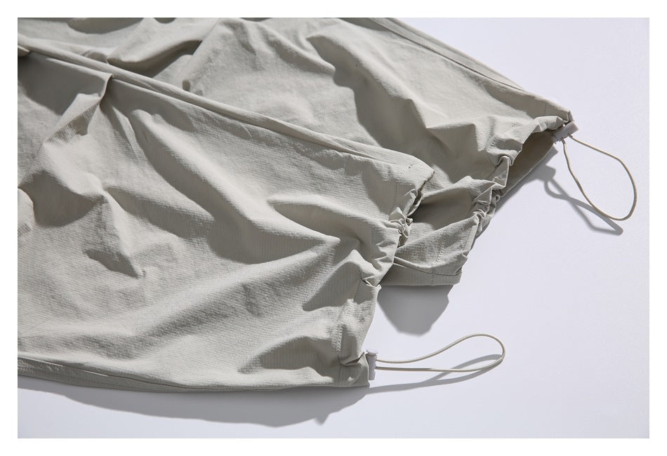 Close-up of the light gray-beige trousers' adjustable leg opening with a drawcord and toggle.