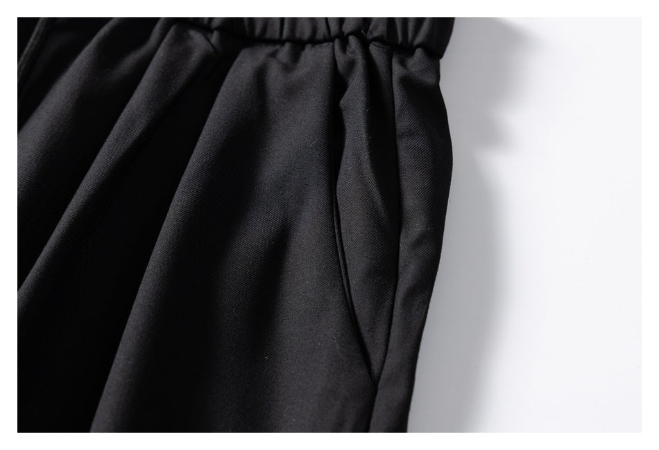 Close-up of black trousers showing a side pocket opening beneath the gathered waistband.