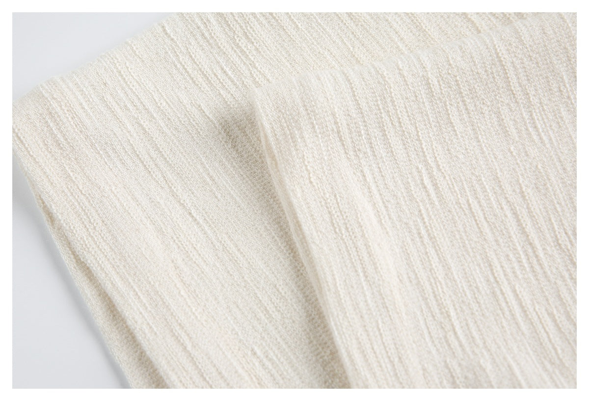 Close-up of ivory ribbed knit fabric with a folded edge and seam.