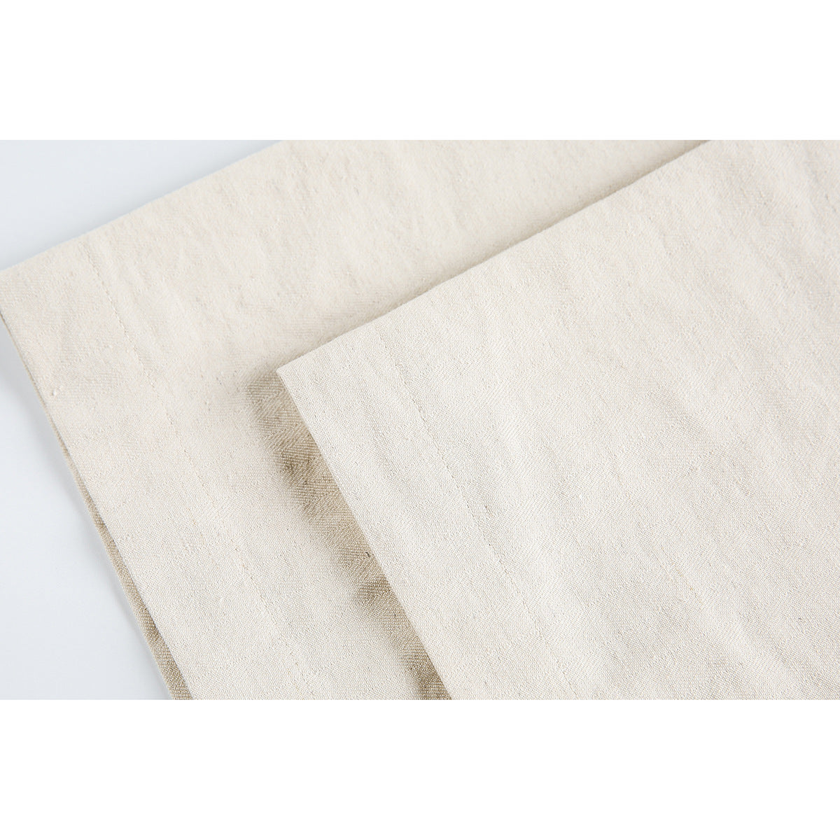 Close-up of ivory fabric folded to show its weave and stitched edge.
