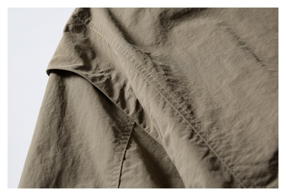 Close-up of a stitched seam and overlapping panels on wrinkled taupe garment fabric.