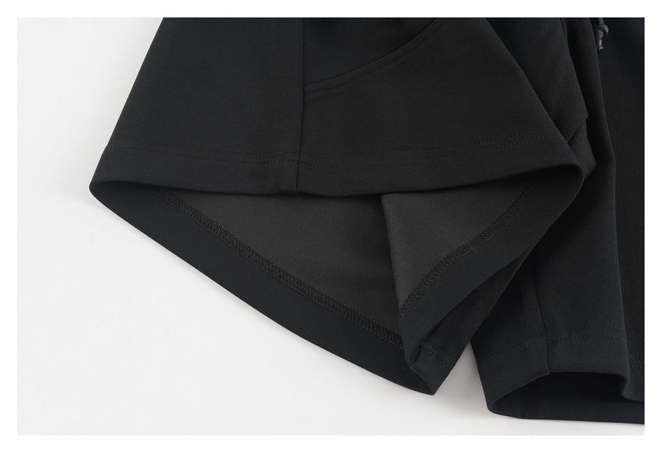 Close-up of the black pants' folded leg hem and visible interior overlock stitching.