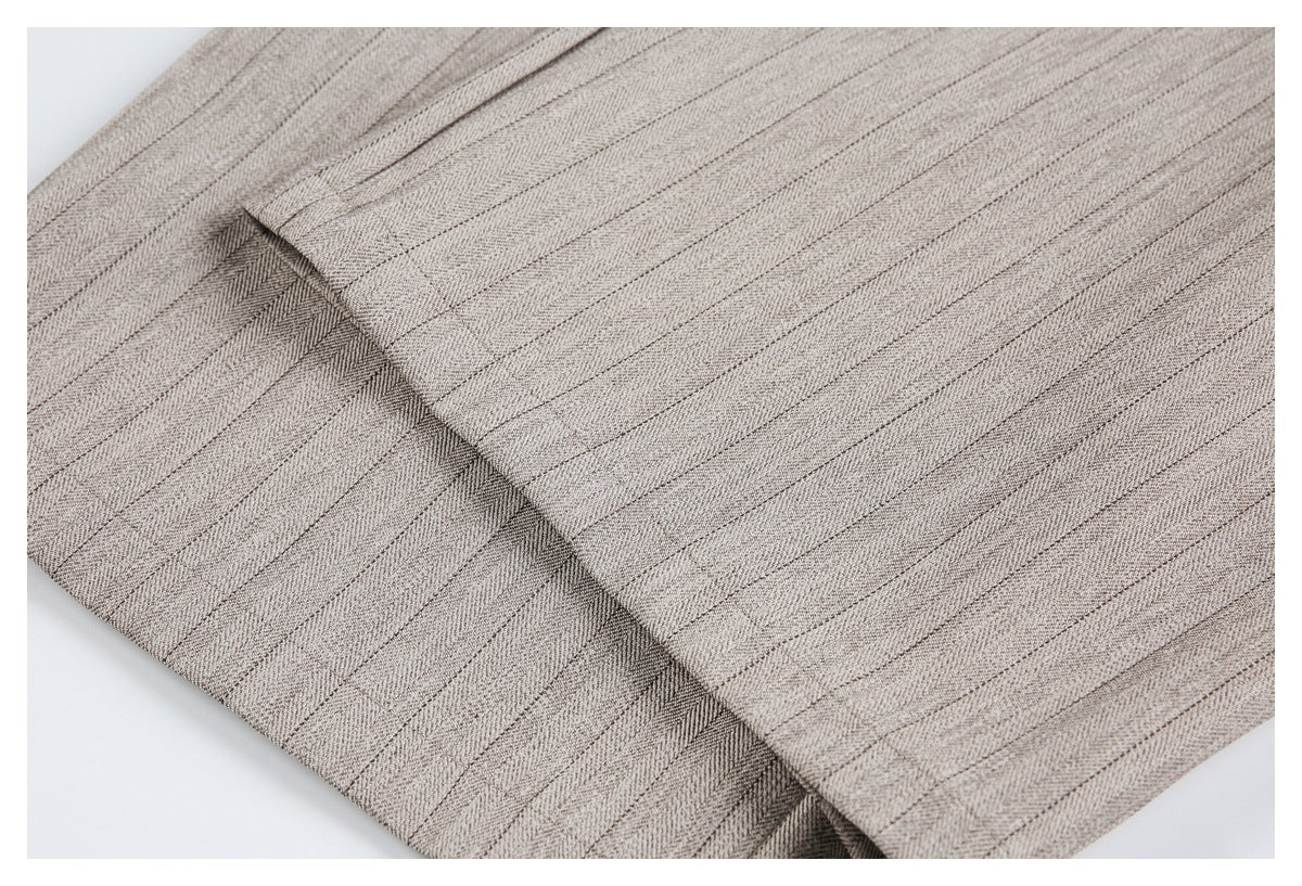 Close-up of a folded edge and stitching on taupe-gray herringbone trousers.