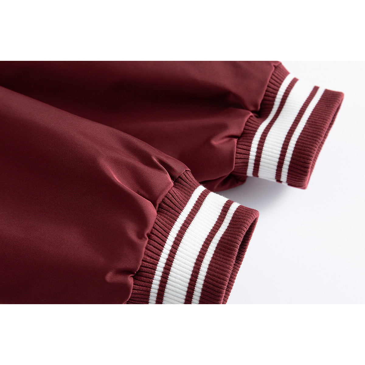 Close-up of burgundy jacket sleeves with burgundy-and-white striped rib-knit cuffs.