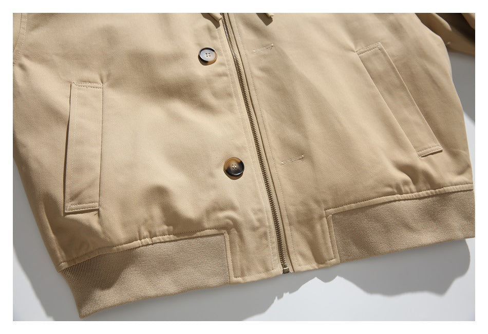 Cropped front of a tan jacket with a zipper, buttons, angled pockets, and ribbed hem.