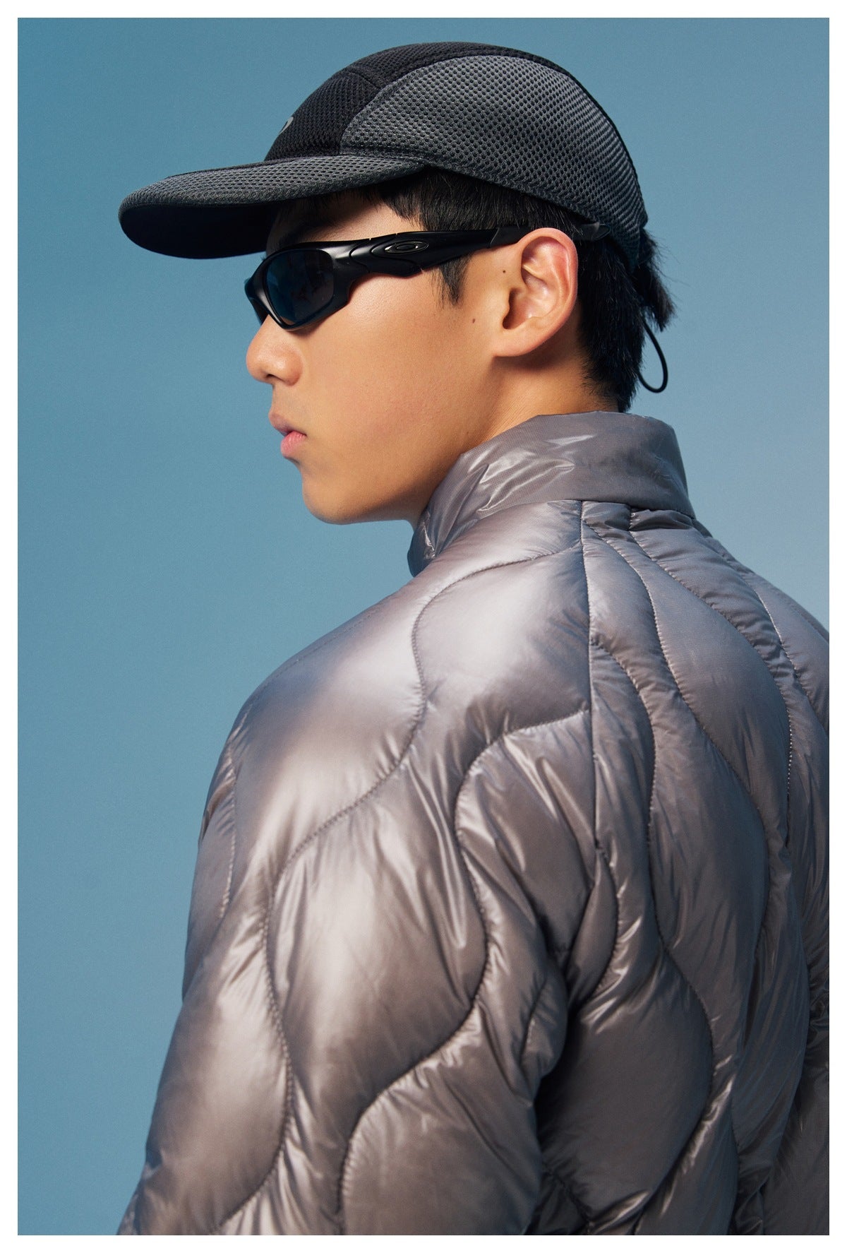 Close side view of a model wearing a charcoal quilted jacket, showing the raised collar and curved shoulder stitching.