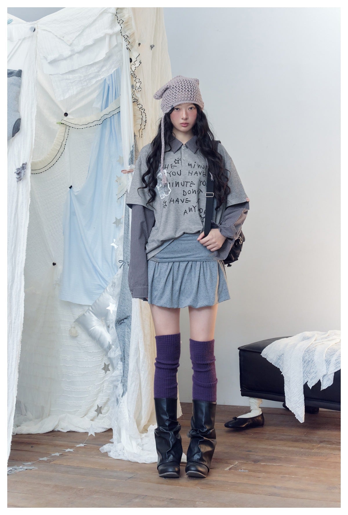 Model facing forward in a gray graphic top with checked long sleeves and a matching gray mini skirt.