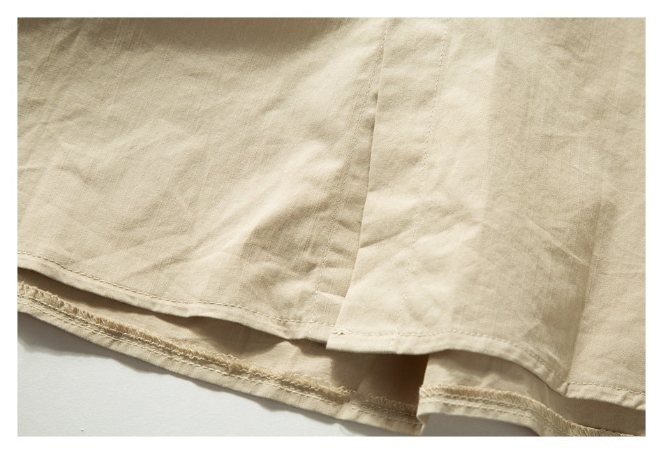 Close-up of the beige shirt's lower hem, showing the stitching and side opening.