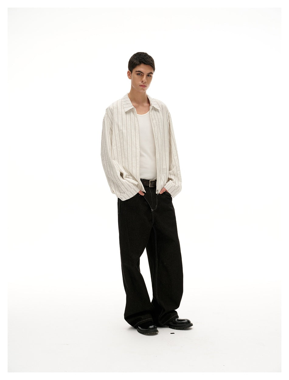 Model wearing open cream pinstriped jacket over white tank top and black wide-leg jeans, hands in pockets