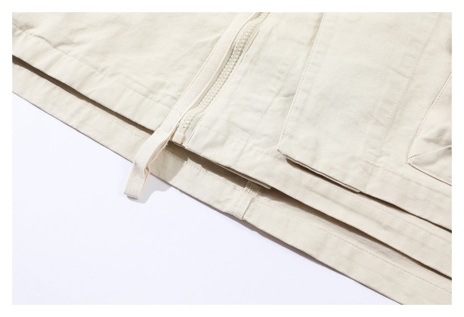 Close-up of an ivory garment's hem, panel seams and zipper with a fabric pull tab.