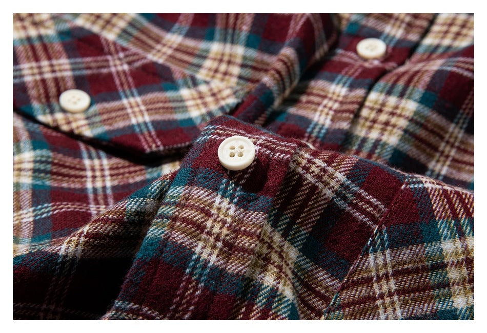 Close-up of cream buttons and plaid shirt fabric in burgundy, teal, cream, and brown.