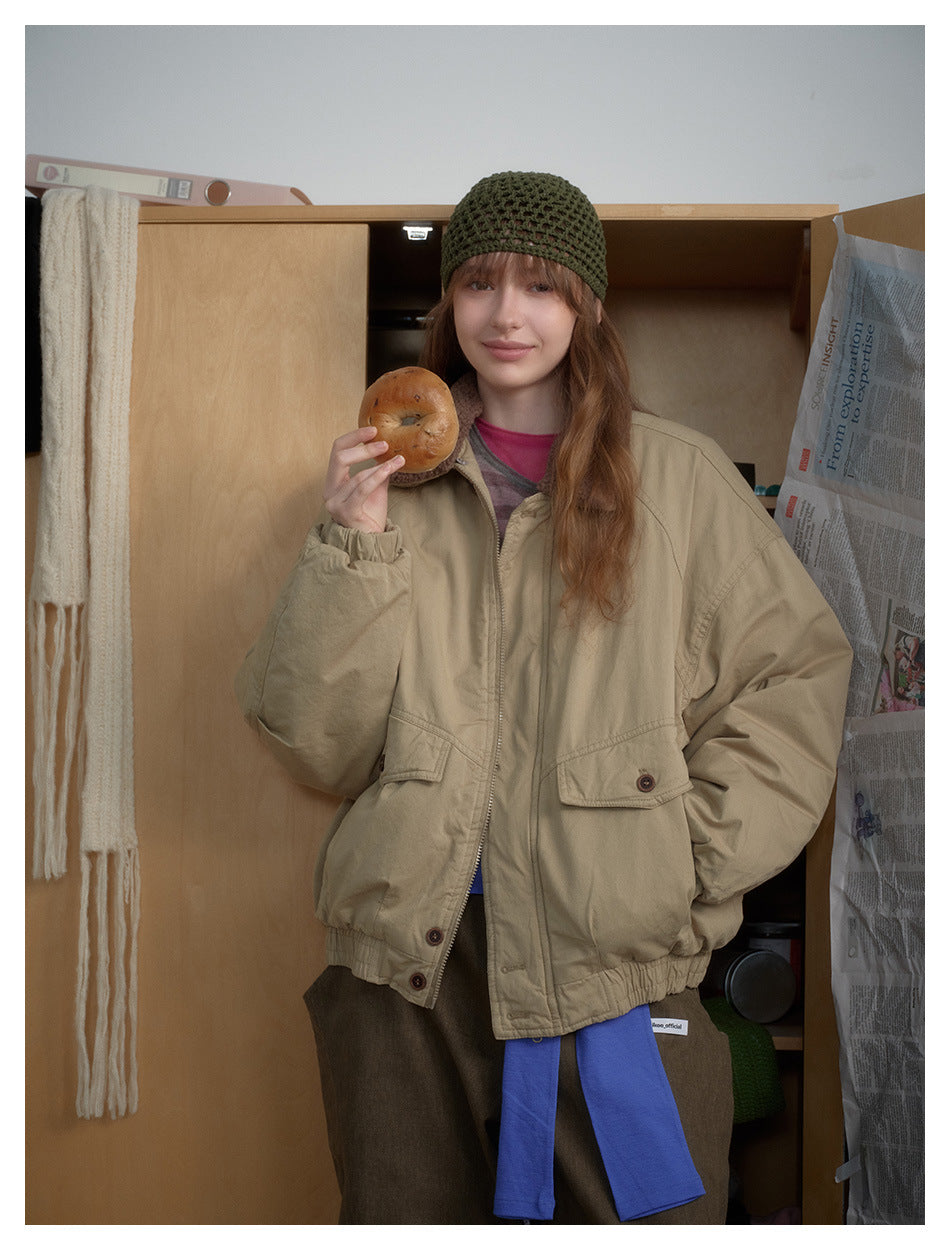 Model wearing a beige zip-front jacket with oversized sleeves, flap pockets and a brown collar; front view.