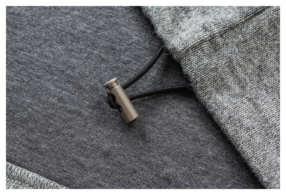 Close-up of a black drawcord with a metal toggle against dark gray knit fabric.