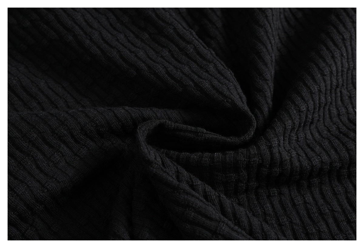 Close-up showing the soft folds and raised ribbed texture of black fabric.