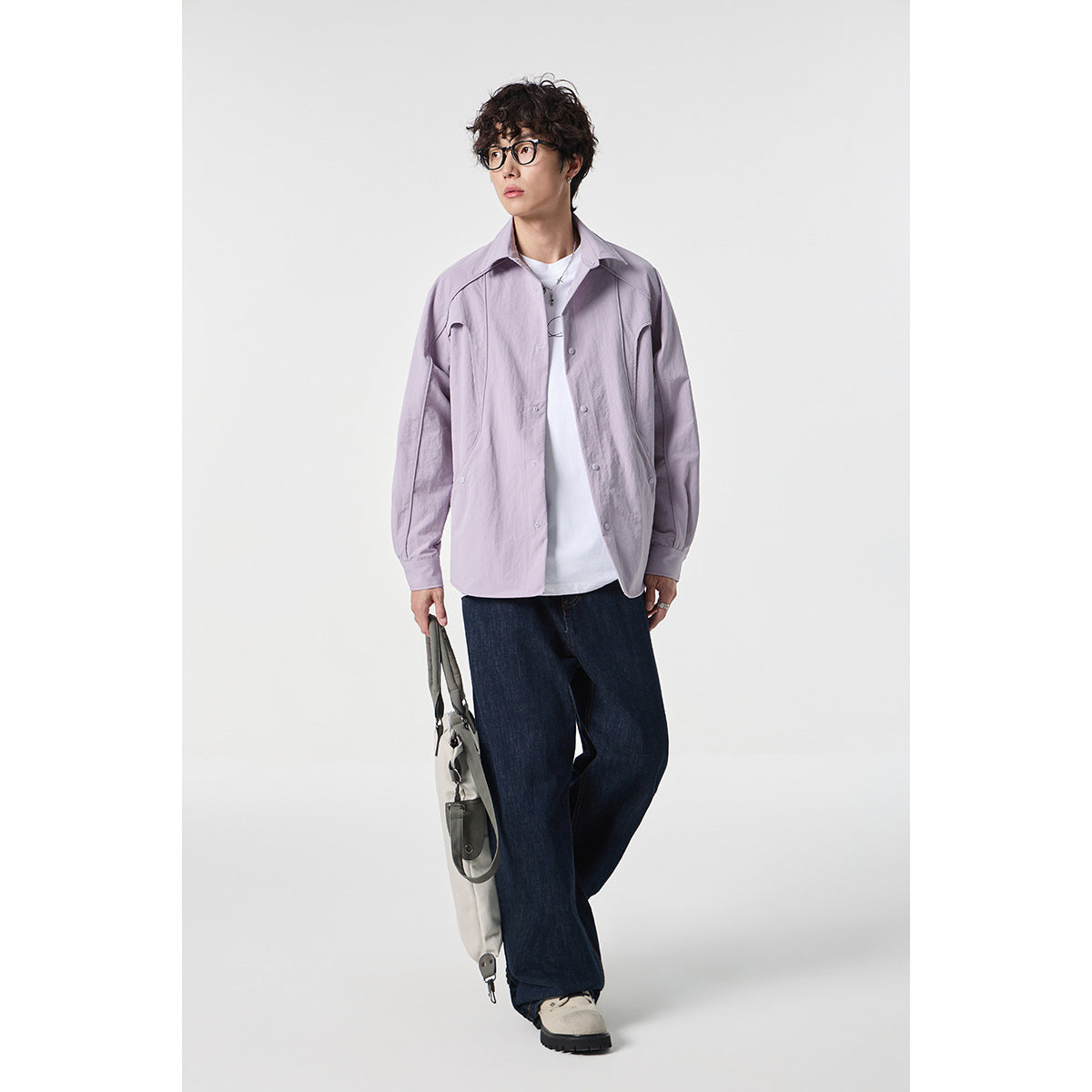Model wearing an open pale lilac collared shirt over a white tee, with dark wide-leg jeans.