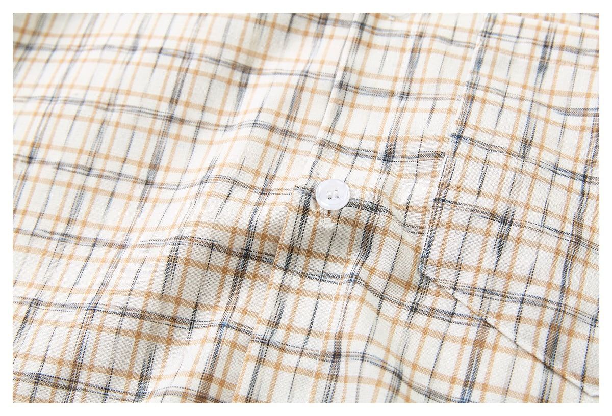 Close-up of the cream plaid shirt chest pocket, button, and intersecting tan and dark gray lines.