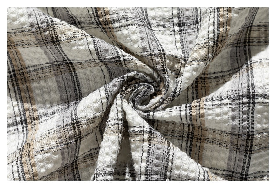 Close-up of cream plaid fabric gathered into folds, showing its raised dotted texture.