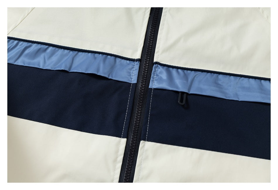 Close-up of an ivory jacket with pale blue and navy horizontal chest panels and a black center zipper.