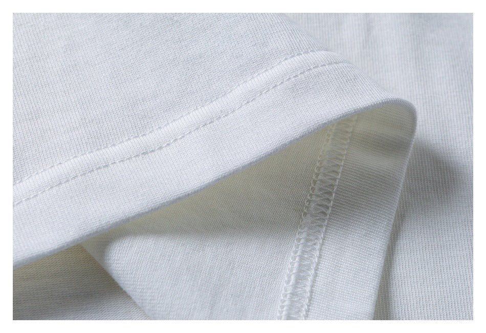 Close-up of white knit garment fabric showing a folded hem and overlocked seam stitching.
