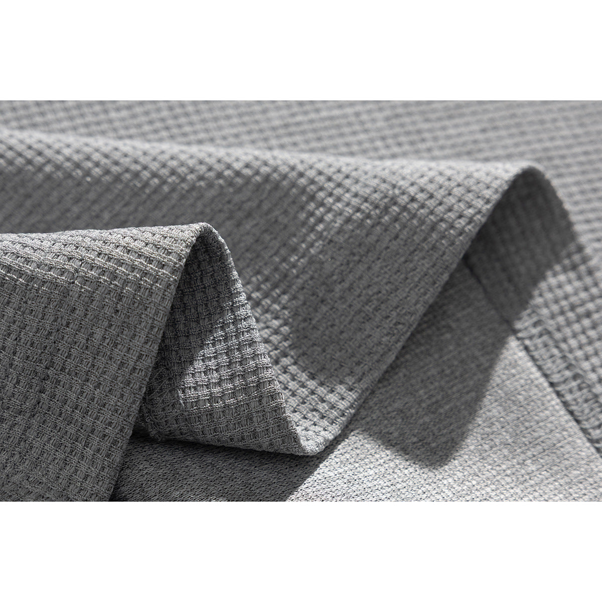 Close-up of light gray fabric folded to show its raised, grid-like texture.
