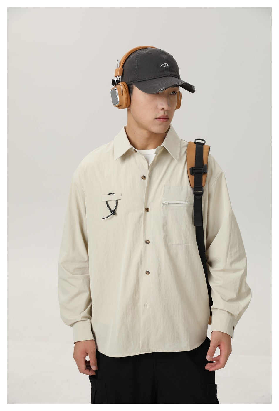 Front view of an ivory button-up shirt with a zip chest pocket and cord detail, worn with a backpack.
