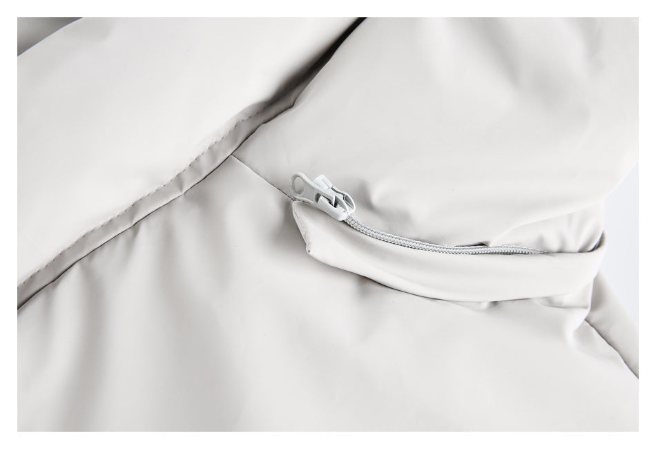 Close-up of a light-colored zipper and pocket on the light beige coat.
