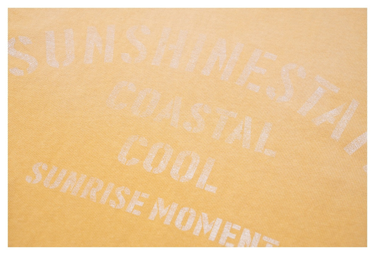 Close-up of pale English lettering printed across the golden-yellow sweatshirt fabric.