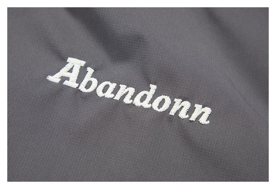 White embroidered lettering on gray jacket fabric.