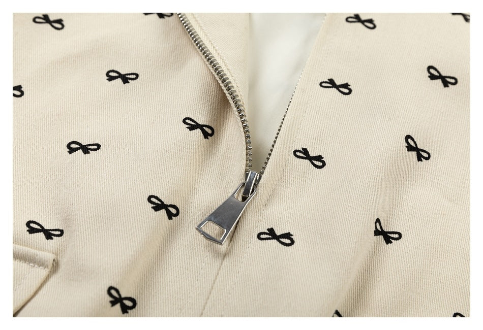 Close-up of the jacket's silver zipper and pull on cream fabric printed with small black bows.