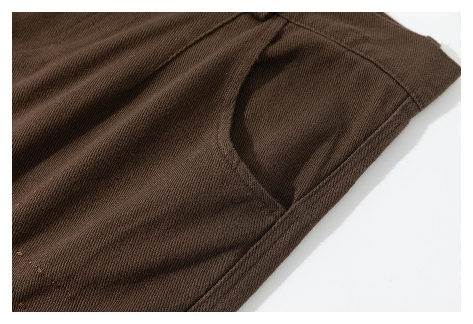Close-up of brown trouser fabric and the curved stitching around a pocket opening.
