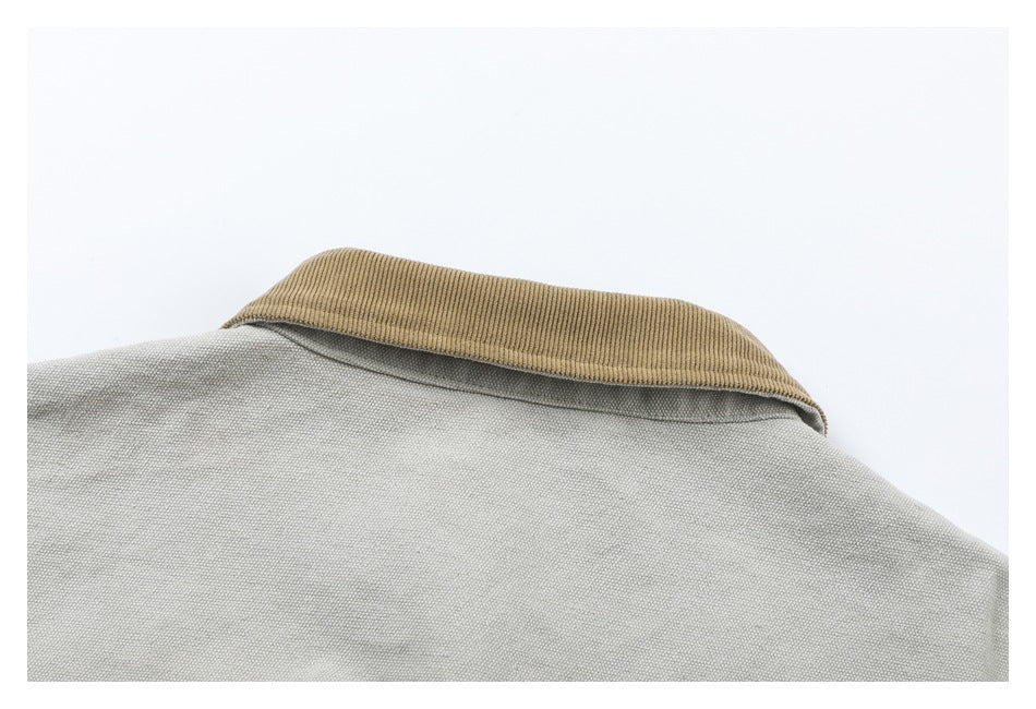 Close-up of the back collar, trimmed with tan ribbed fabric, on a light gray garment.